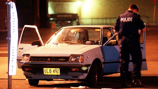 A forensic officer inspects a bullet-riddled car in Hughes Street, Cabramatta, after a shooting in January 2000. Picture: Jim Trifyllis 