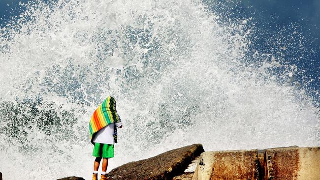 A big swell hits the Gold Coast. A man watches waves crash over the rocks at The Spit.