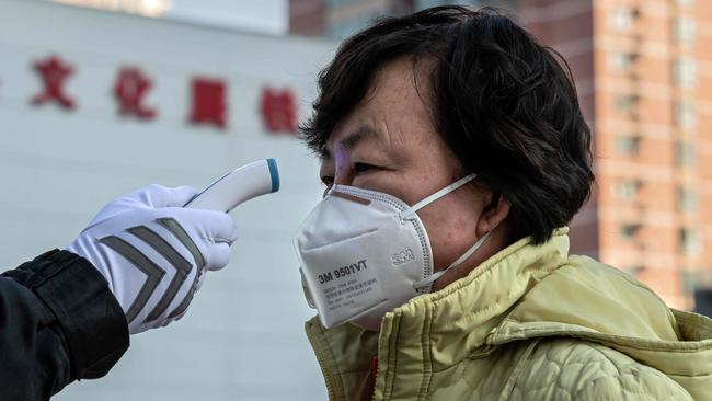 A security guard checks the temperature of a woman in the Chinese city of Wuhan.