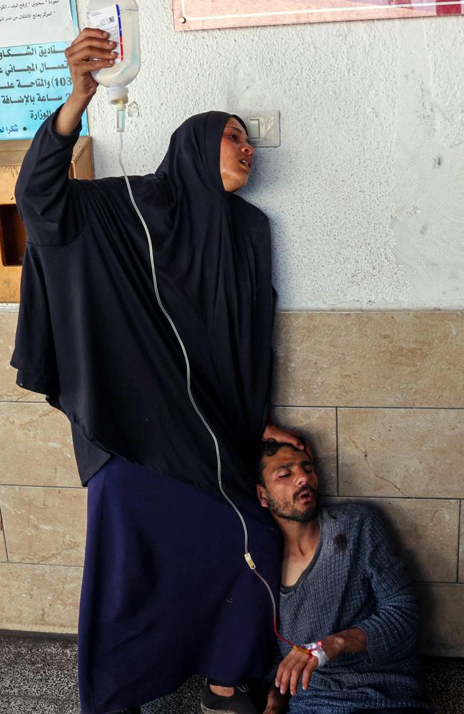 A Palestinian woman assists an injured man outside Al-Najjar Hospital in Rafah, in the southern Gaza Strip. Picture: Said Khatib/AFP