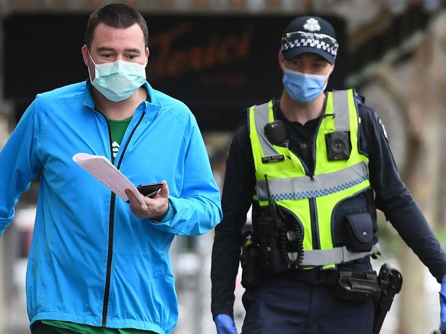 Police issue a fine to a man breaking lockdown laws in Melbourne on August 9, 2020, as the city struggles to cope with a COVID-19 coronavirus outbreak. - Australia's worst-hit Victoria state reported 17 deaths from coronavirus on August 9, making it the country's deadliest day of the pandemic despite a fall in new case numbers. (Photo by William WEST / AFP)