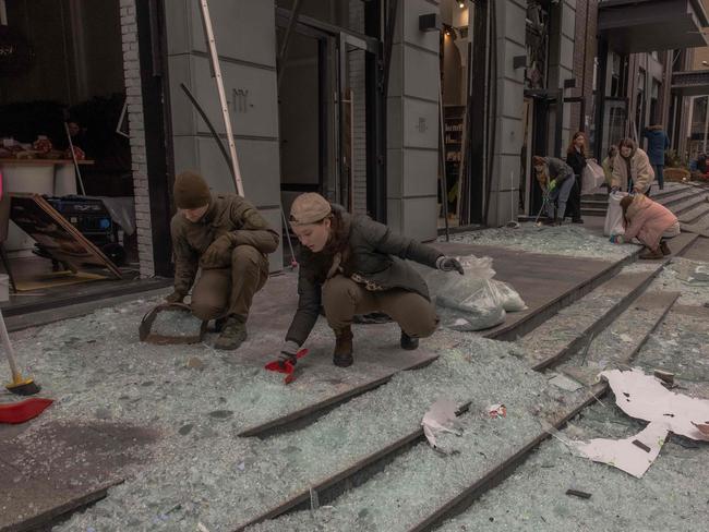 People clean up broken glass following the strike. Picture: AFP