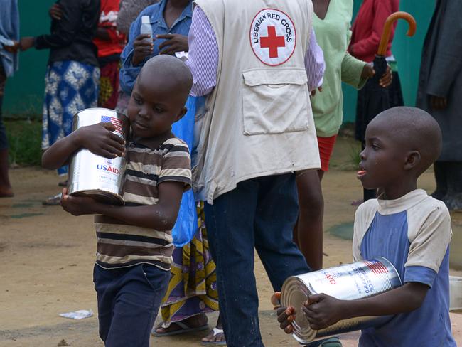 Boys carry food cans during a food distribution by the World Food Programme (WFP) in Dolo's Town, some 60 km east of Monrovia, quarantined as a measure to contain the spread of Ebola on September 2, 2014. International medical agency Medecins sans Frontieres said on September 2 the world was "losing the battle" to contain Ebola as the United Nations warned of severe food shortages in the hardest-hit countries. The Ebola virus, transmitted through contact with infected bodily fluids, has killed more than 1,500 people in four countries since the start of the year -- almost 700 of them in Liberia. AFP PHOTO / DOMINIQUE FAGET