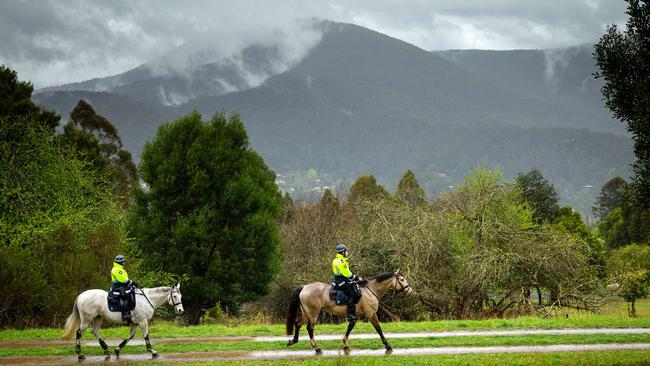 Police on horseback search the rugged terrain. Picture: Mark Stewart