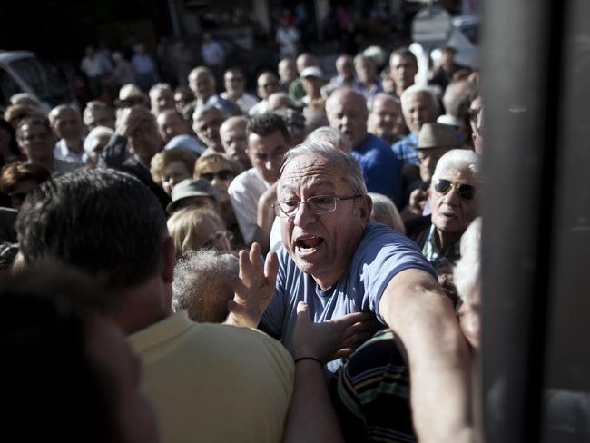 Mad rush ... Pensioners try to enter a national Bank branch, as Greece reopened banks for pensioners who do not use cash cards for ATM. Picture: AFP/ANGELOS TZORTZINIS