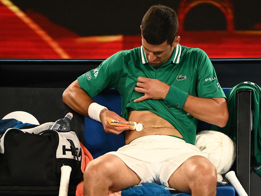 Novak Djokovic of Serbia rubs cream into his side.