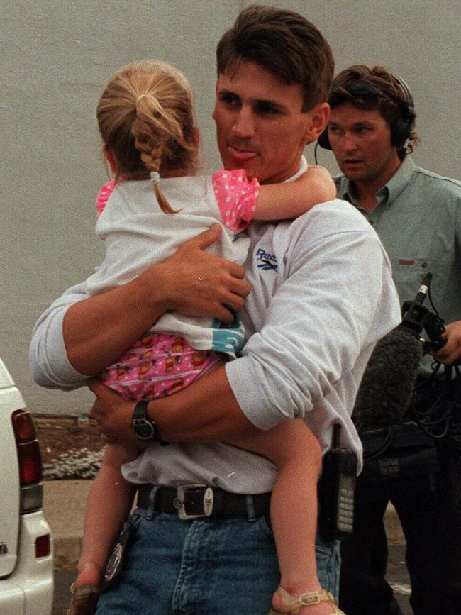 Plain clothes police carry a child from the scene in 1997.