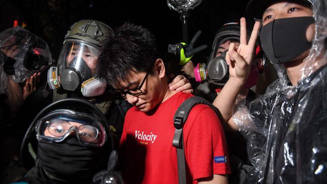 Young demonstrators pose for photographs with a man they suspect of spying for the police. Picture: AFP