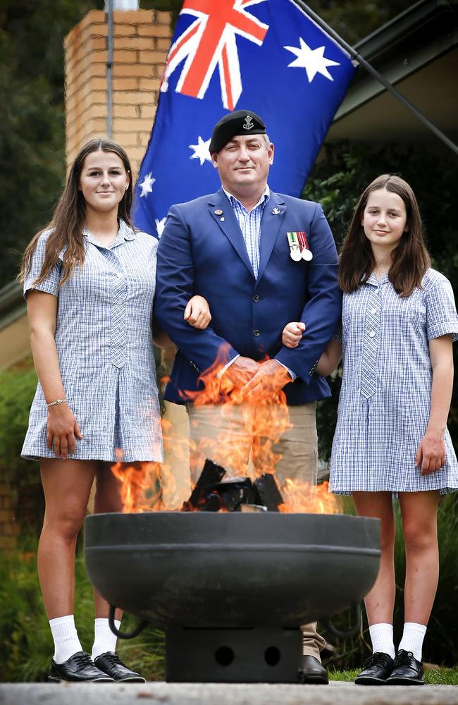 Former Australian Army soldier Chris McAleer is going to set up a fire pit at the end of his driveway in Kilsyth as a tribute to Anzac Day. Chris stands at his steel fire pit he made himself with his daughters Caitlyn, 16, and Alannah, 12. Picture: David Caird