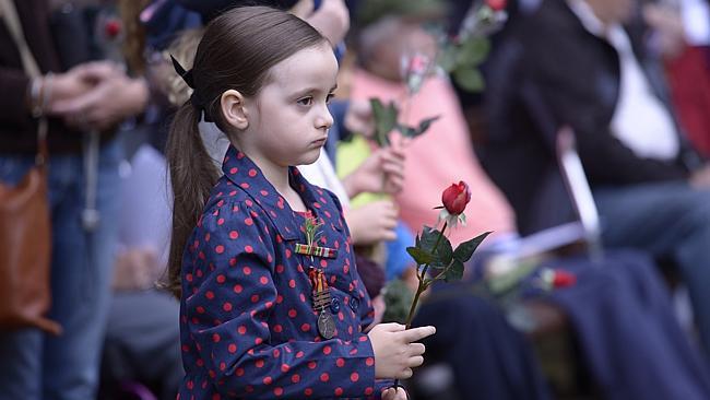 A child holds a rose at the Anzac Service at Turramurra.                              Picture: DAVID SWIFT