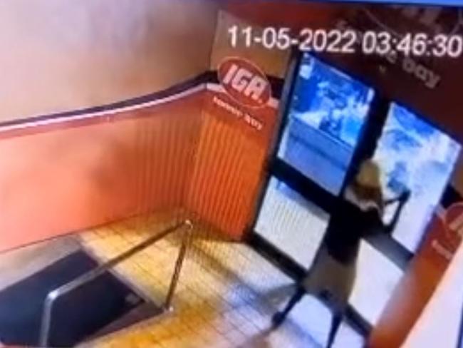 CCTV catches an unidentified offender hacking into the front door glass of the IGA Fannie Bay with an axe. Picture: Supplied.