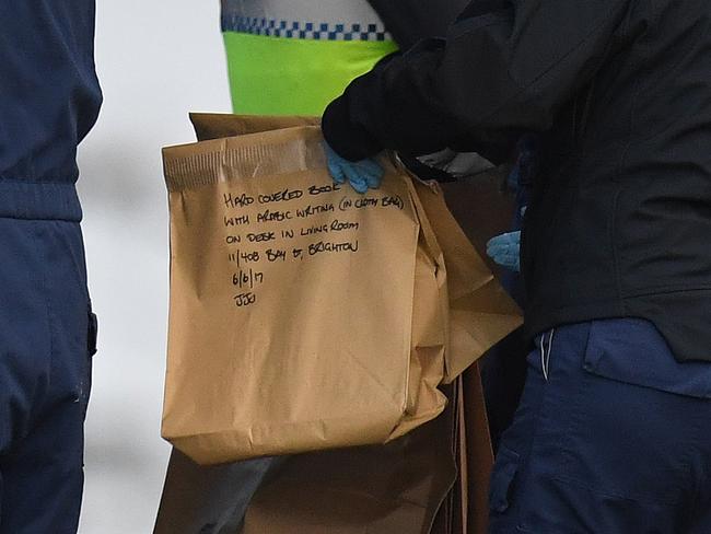 Forensic police hold an evidence bag outside the Buckingham Serviced Apartments. Writing on the bag says: “Hard covered book with Arabic writing (in cloth bag) on desk in living room. Picture: AAP