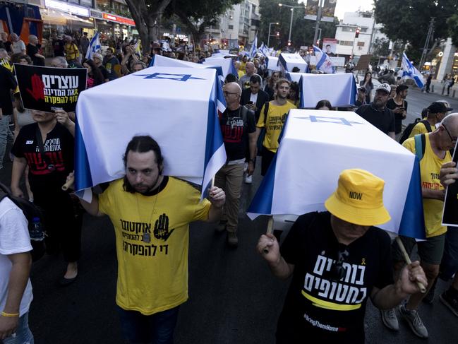 TEL AVIV, ISRAEL - SEPTEMBER 5: Protesters carry staged coffins covered with Israeli flags to represent 27 hostages killed in Hamas captivity in the Gaza Strip during a rally calling for a hostages deal with Hamas on September 5, 2024 in Tel Aviv, Israel. The public marched from Habima Square, where 27 coffins draped in Israeli flags were placed, to the Begin Gate at the Kirya, where they paid final respects to those killed by Hamas in captivity. (Photo by Amir Levy/Getty Images)