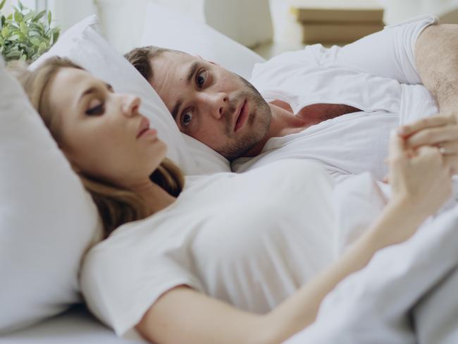 Closeup of couple with relationship problems having emotional conversation while lying in bedroom at home