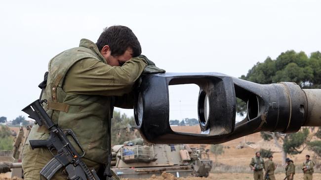 An Israeli soldier rests his head on an artillery gun barrel of an armoured vehicle as Israeli soldiers take positions near the border with Gaza in southern Israel. Picture: AFP