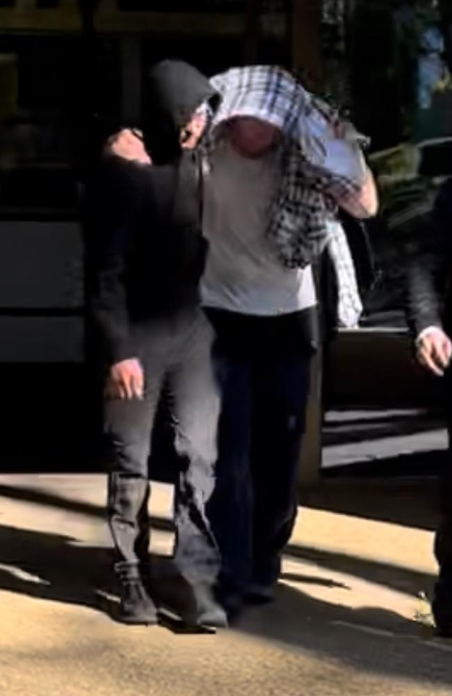 Nathan Bernhard leaving Nowra Police Station, hidden under blanket. Picture: Tom McGann