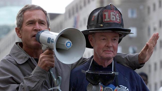 George W. Bush speaks to volunteers and firemen as he surveys the damage at the site of the World Trade Centre.