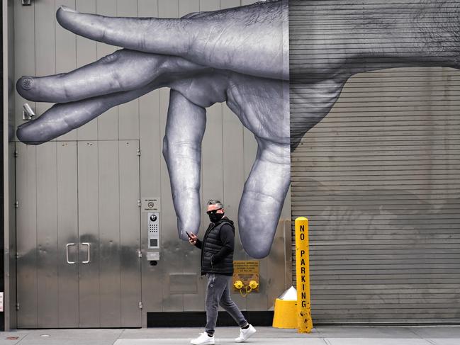 A man wearing a protective mask walks by street art amid the coronavirus pandemic in New York City. Picture: Getty Images