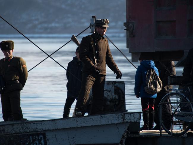 A North Korean soldier (right) stands on a boat on the Yalu River at the town of Sinuiju across from the Chinese border town of Dandong at the weekend. A decade of imposed sanctions has failed to prevent Pyongyang from scaling up its nuclear and ballistic missile programs, a UN panel of experts has concluded. Picture: Johannes Eisele