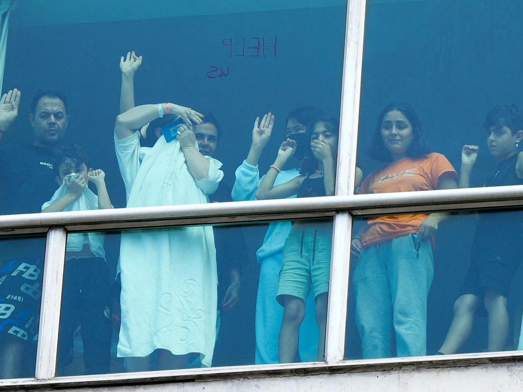 Migrants deported from the US gesture as they look out the window of the Decapolis Hotel where they are temporarily staying in Panama City. Picture: AFP