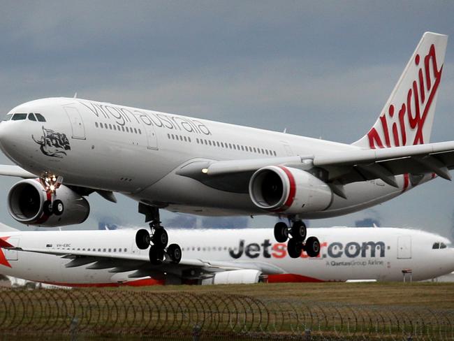 A Virgin Australia A330-200 lands past a former QANTAS now Jetstar A330-200 (VH-EBC) at Melbourne Airport.
