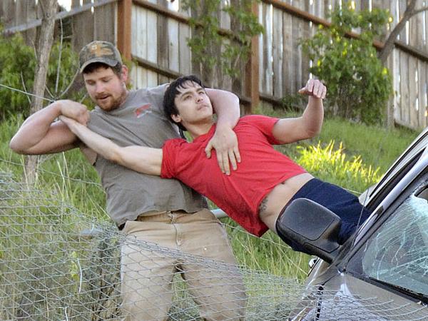 ADDS IDENTIFICATION OF DRIVER AND RESCUER- Jason Warnock, left, pulls Mathew Sitko, to safety from an SUV stopped by a chain link fence just short of a 30-foot vertical drop onto Bryden Canyon Road, Wednesday, April 15, 2015, in Lewiston, Idaho. The 23-year-old driver suffered minor injuries and was taken to a hospital, according to authorities. (Barry Kough/Lewiston Tribune via AP)