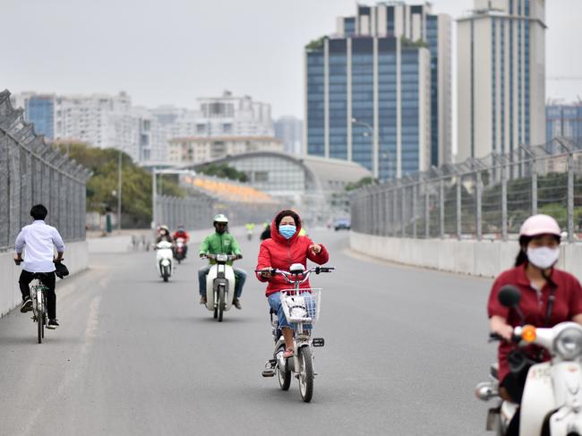 Motorists, wearing face masks amid concerns of the Covid-19 outbreak, ride past the Formula One Vietnam Grand Prix racetrack site in Hanoi. Picture: AFP