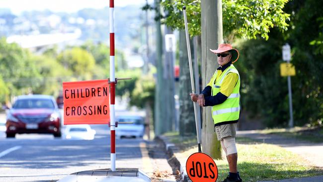 A pedestrian crossing attendant Peter performs his duty outside a primary school, even though most students stayed home, in Brisbane. Picture: AAP/Dan Peled