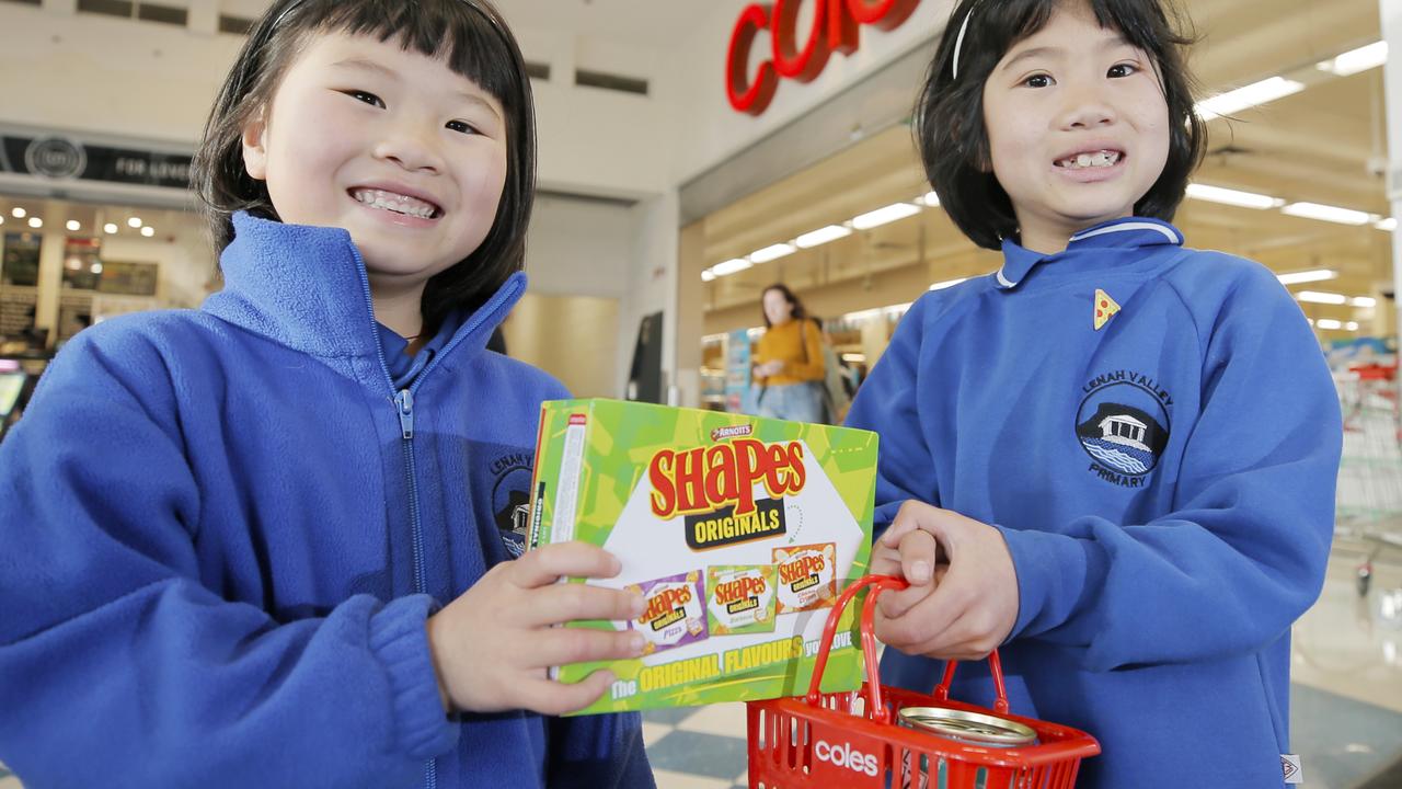 Katie, 7, and Emily Yan, 5, try to squeeze some barbecue Shapes into a shopping basket from the Coles Tiny Shop collectables series during their shop at Coles.