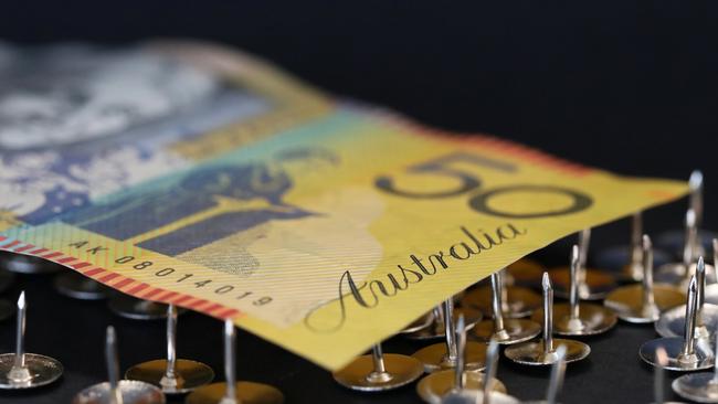 close up extreme shallow depth of field macro shot of australian fifty dollar note supported on sharp thumb tacks or drawing pins. Finance business economy concept. Debt trap generic money