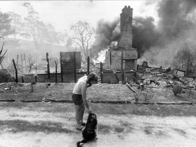 Ron Rowe with his distressed dog Pepper outside the blazing remains of his historic home at Paechtown on February 16, 1983.