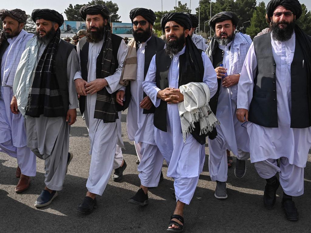 Taliban spokesman Zabihullah Mujahid (third from right) arrives as he is accompanied by officials to address a media conference at the airport in Kabul. Picture: AFP