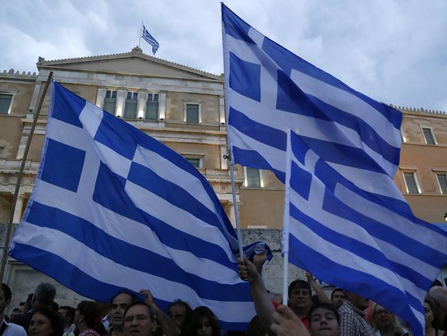 Demonstrators hold Greek flags during a rally organized by supporters of the YES vote.