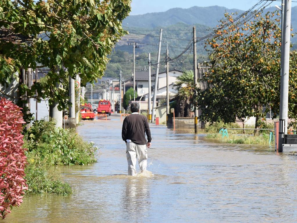 A resident walks on a flooded road in Date, Fukushima prefecture on October 13, 2019, one day after Typhoon Hagibis swept through central and eastern Japan. Picture: AFP/Japan OUT