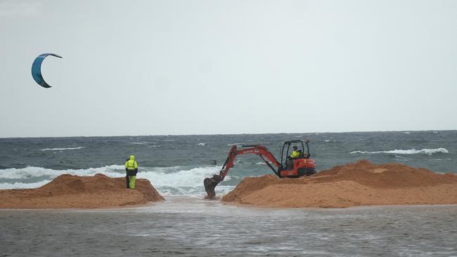 An excavator works through the build up of sand on North Narrabeen Beach as the council makes an opening to release water from Narrabeen Lagoon in 2020. Picture: Jeremy Piper