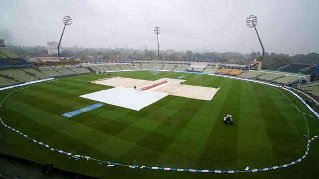 Ground staff cover the field as rain falls before the scheduled start of play on day five. Picture: AFP