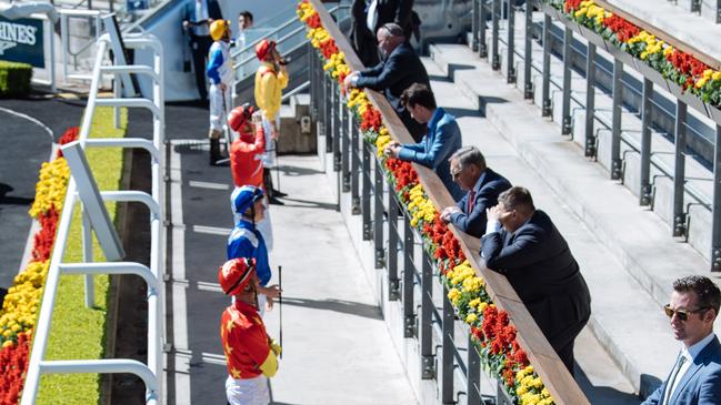 Jockeys and trainers keep their distance at Royal Randwick as part of strict protocols to ensure the sport can continue.