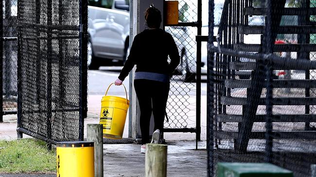 A person collects syringes from the ground in a carpark in Richmond.