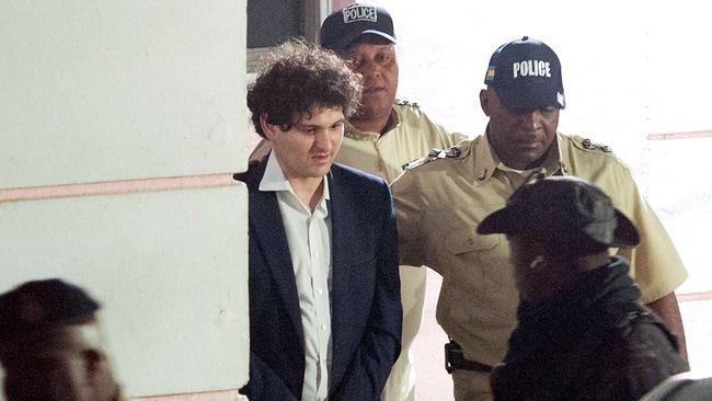 FTX founder Sam Bankman-Fried is led away handcuffed by officers of the Royal Bahamas Police Force in Nassau, Bahamas on December 13, 2022. (Photo by Mario DUNCANSON / AFP)