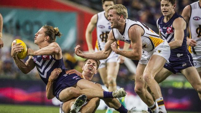 Nat Fyfe gets a hand ball away despite the attention of Daniel Howe and Will Langford. Picture: AAP