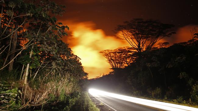 As lava activity erupts in the background, cars drive down Hwy 132, Friday, May 18, 2018, near Pahoa, HI. (AP Photo/Marco Garcia)