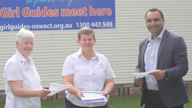 Coffs Harbour MP Gurmesh Singh examines important Girl Guide documents with North Pacific Coast Girl Guides region manager Elise Crofts and Coffs Harbour Girl Guides district manager Susan Gibson.