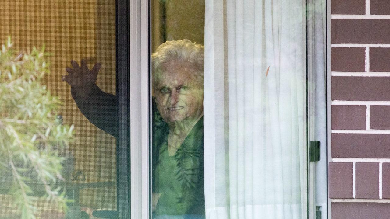 Patricia Shea, 76, who was diagnosed with COVID-19, waves to her son from the window of her accommodation at Newmarch House residential care in Caddens, Sydney on May 3. Picture: Damian Shaw