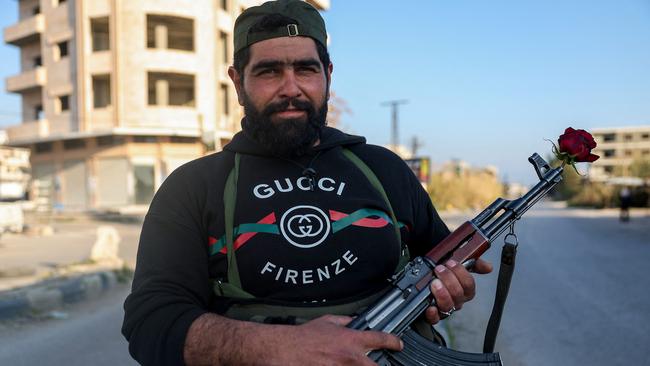 A member of the security forces loyal to the interim Syrian government poses with a AK-47 rifle and a rose at a location previously held by supporters of deposed president Bashar al-Assad, in the town of Hmeimim. Picture: AFP
