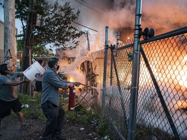 Residents try to put out a car fire in Minneapolis. Picture: AP