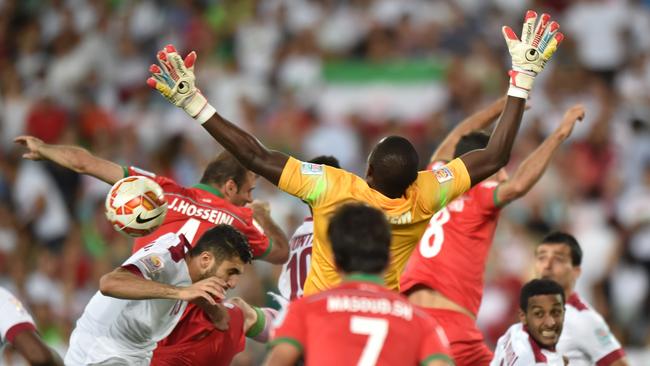 Qatar goalkeeper Qasem Burhan jumps for the ball in a crowd of bodies.