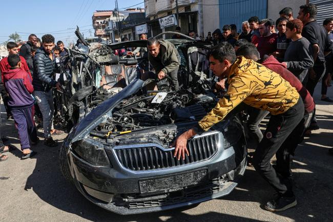 Crowds examine the car in which two journalists were killed in an air strike blamed by Hamas on Israel