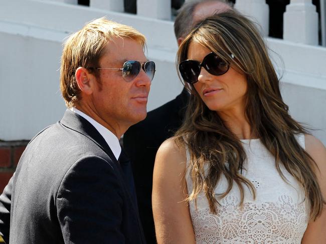 (FILES) In this file photograph taken on July 19, 2013, Australian former cricketer Shane Warne (L) with his fiancee British actress and model Liz Hurley are seen together after he is presented with an award during the tea interval on the second day of the second Ashes cricket test match between England and Australia at Lord's cricket ground in north London. - Australia cricket great Shane Warne, widely regarded as the greatest leg-spinner of all time, has died aged 52 according to a statement issued by his management company on March 4, 2022. Warne's management said he died in Koh Samui, Thailand, of a suspected heart attack. (Photo by Ian KINGTON / AFP)