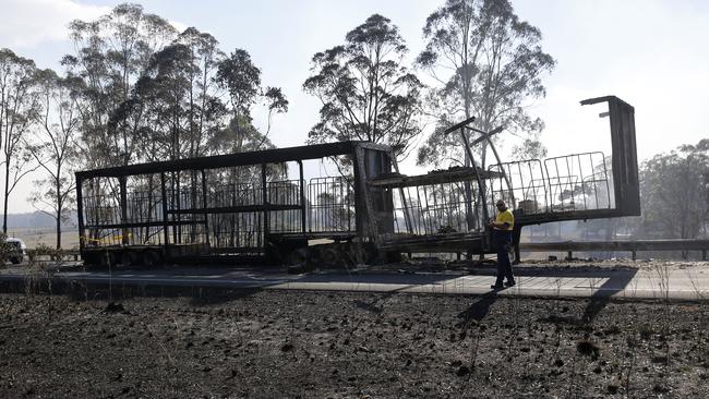 The remains of a B Double trailer smoulders on the Pacific Highway south of Taree on Saturday.