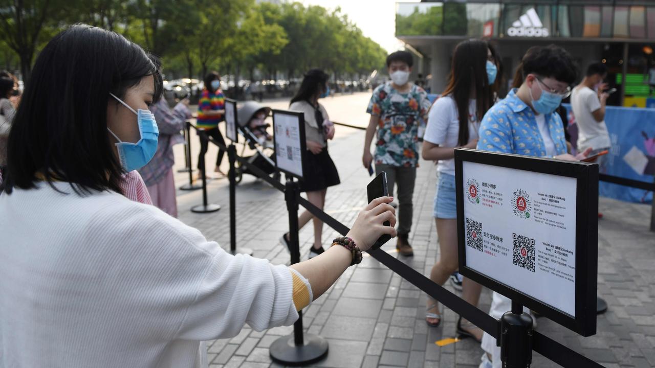 A woman scans a phone code required to prove her health and travel status before being allowed to enter a shopping mall in Beijing. Picture: Greg Baker/AFP